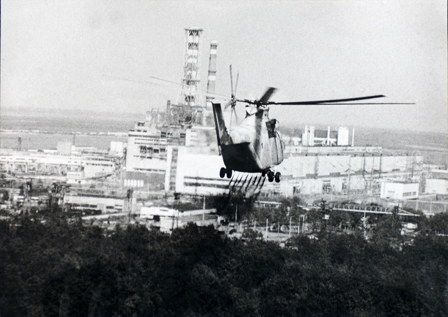 A helicopter moves in to help experts check the damage to the Chernobyl reactor in 1986. (Chernobyl, Ukraine, 1986). Photo Credit: USFCRFC from IAEA Imagebank Flickr